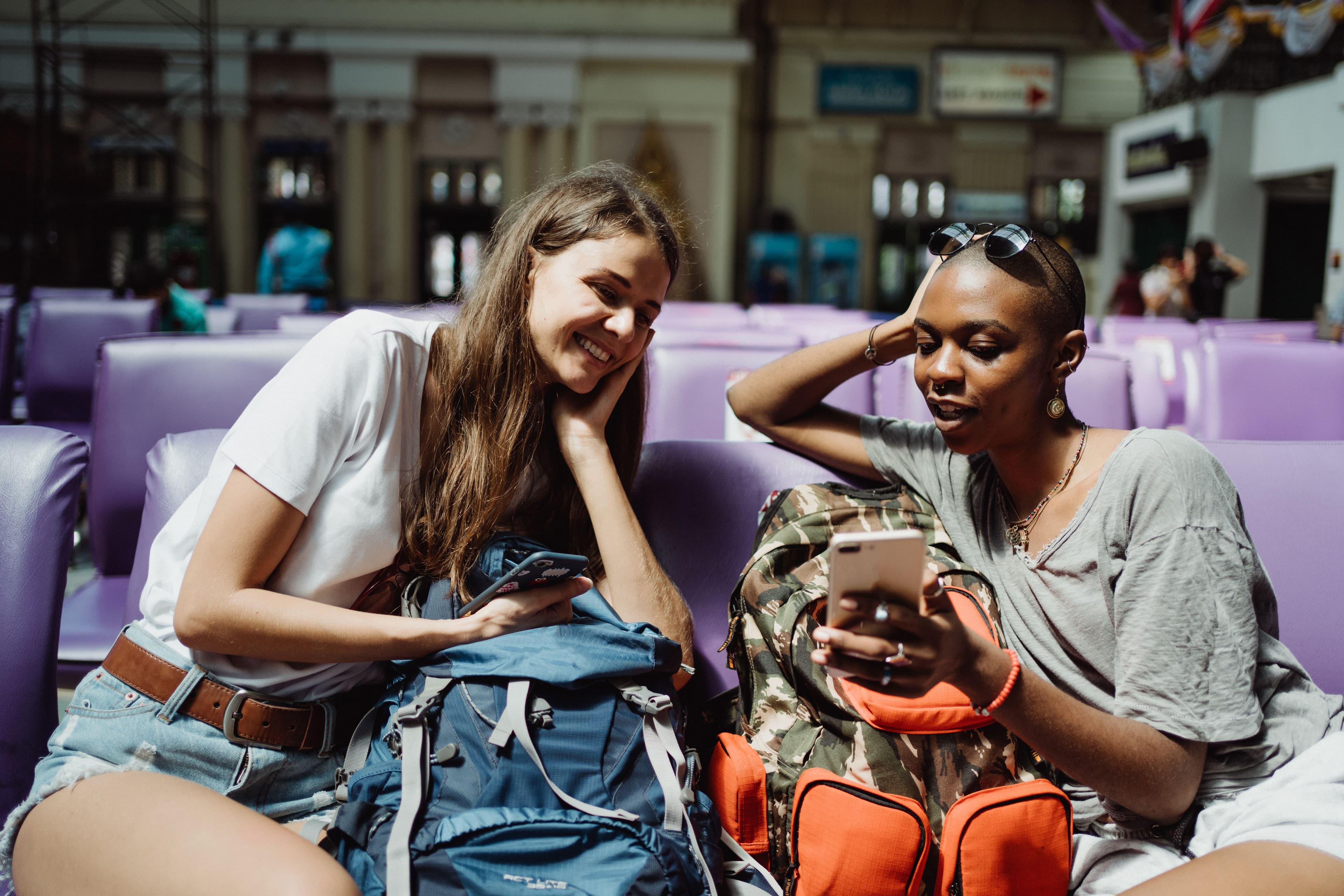 Two travelers laughing while looking at a phone together