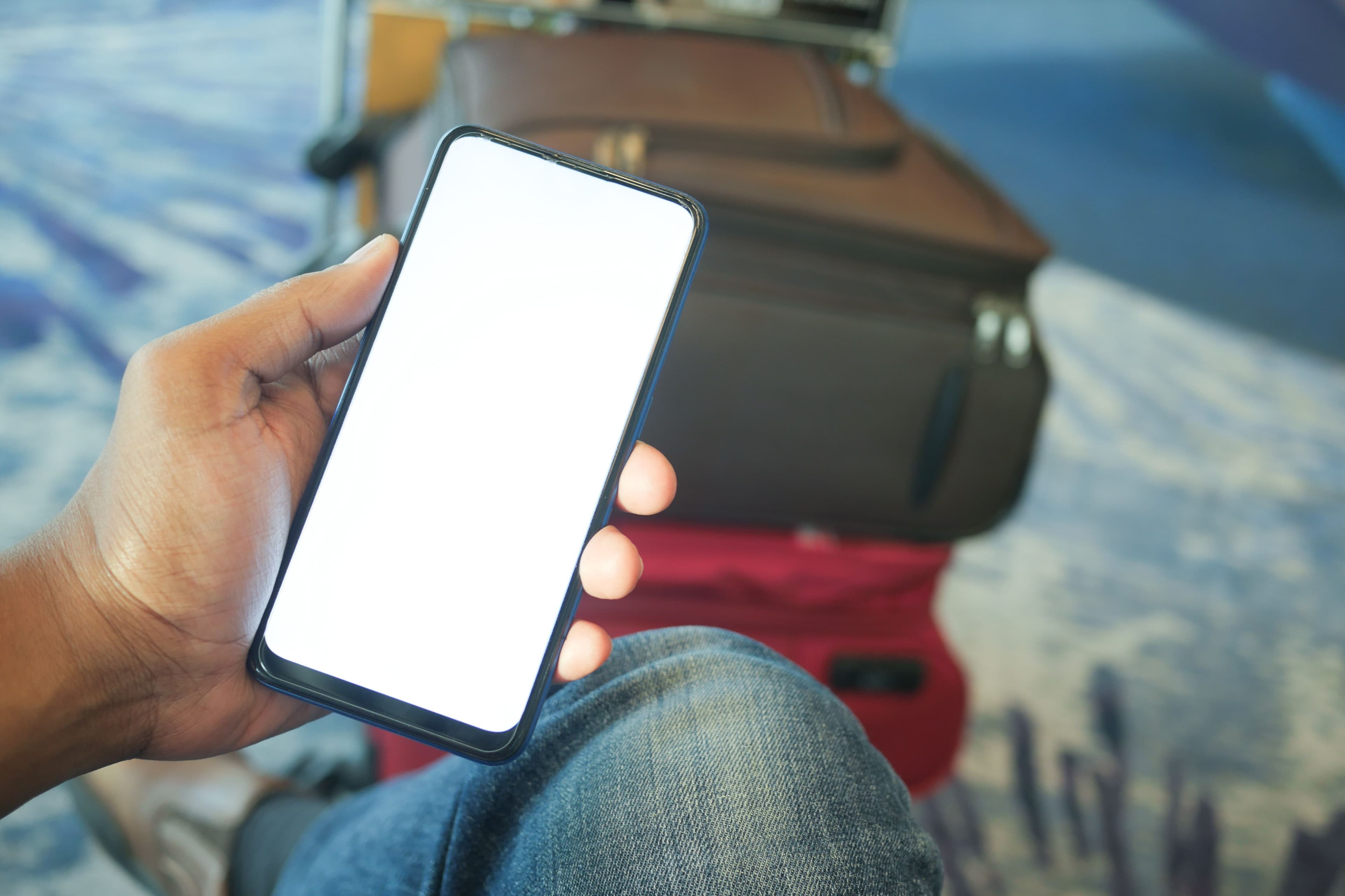 Traveler holding a phone ready to scan an eSIM QR code, luggage in the background